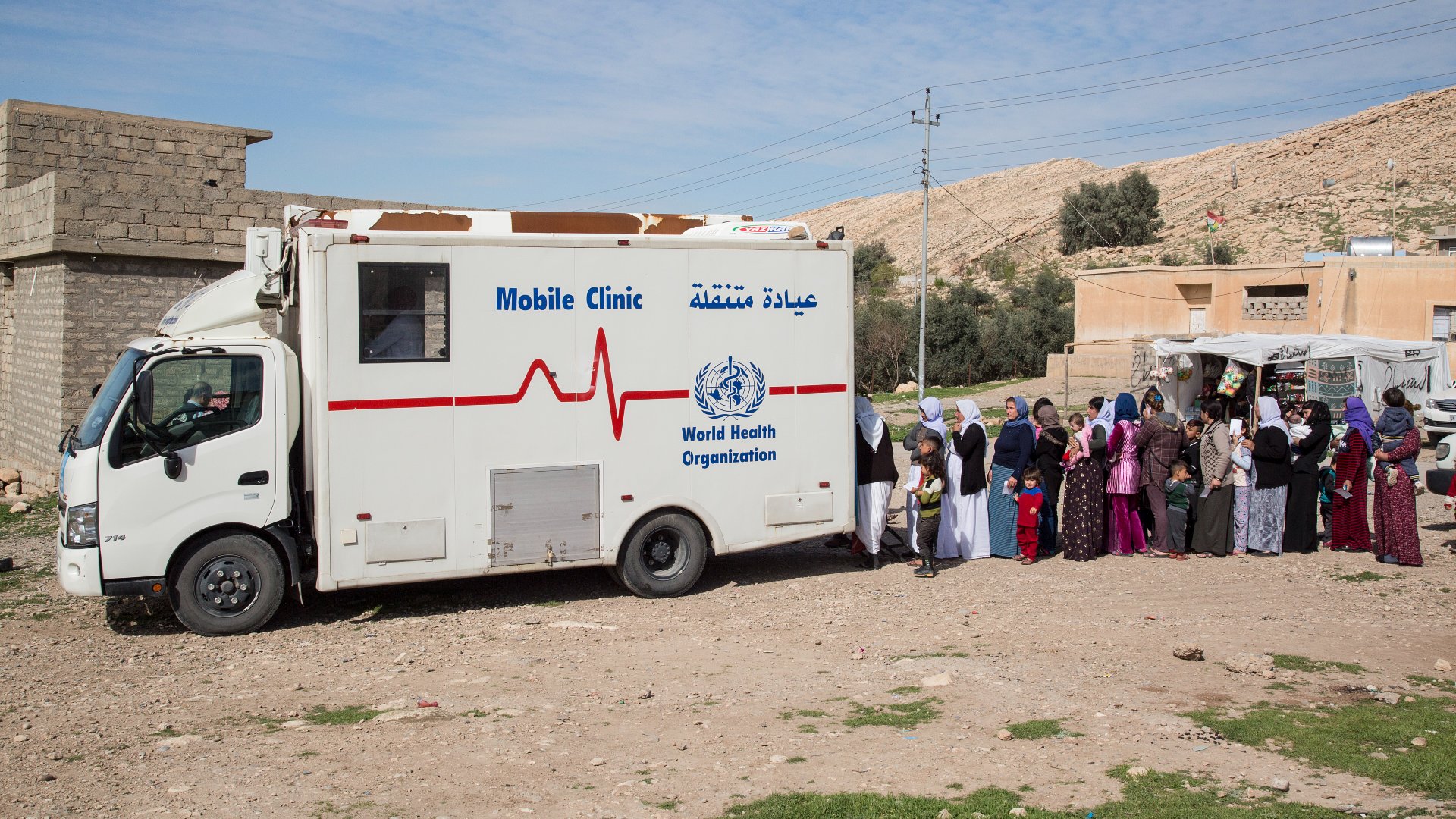 Yezidi men, women and children line up at a Mobile Clinic to get medical attention.