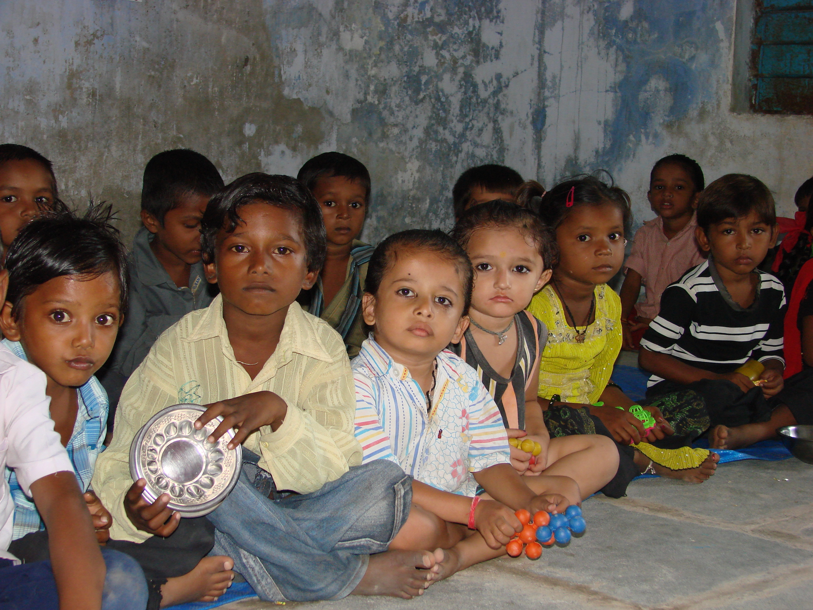 Barefoot children sitting on the floor of their classroom at a school in India