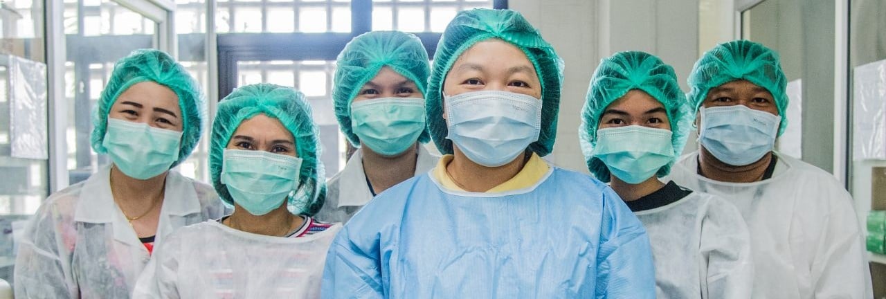 Six medical staff standing in gowns, masks and head caps