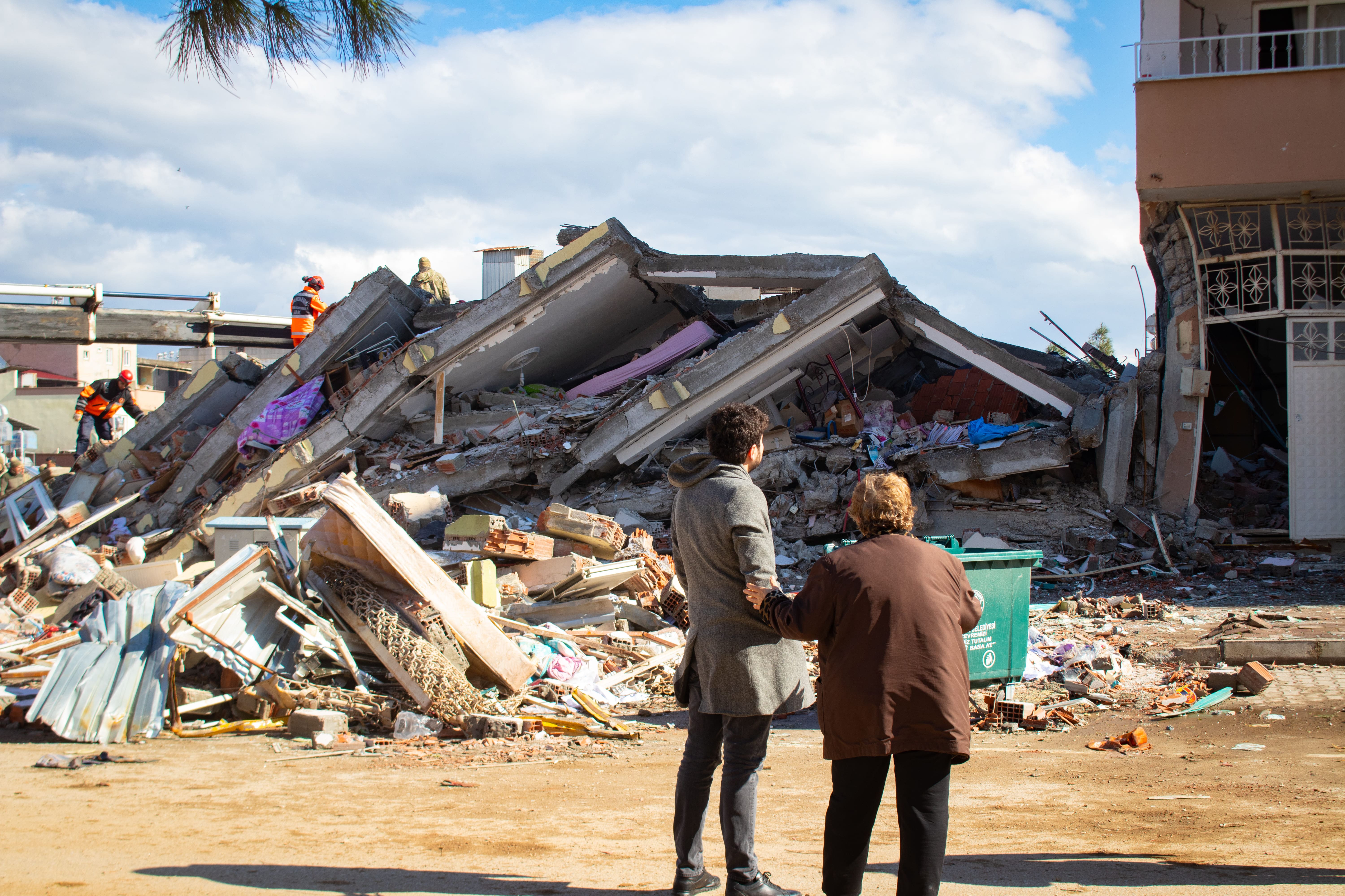 A man and woman look at a collapsed building in Islahyia, Türkiye, on 7 February 2023.