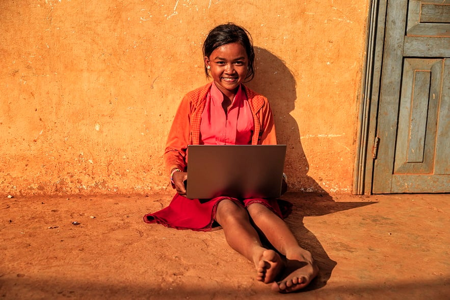 A smiling girl uses a laptop.