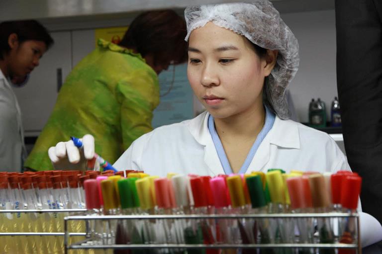 A lab technician in Thailand picking test tubes