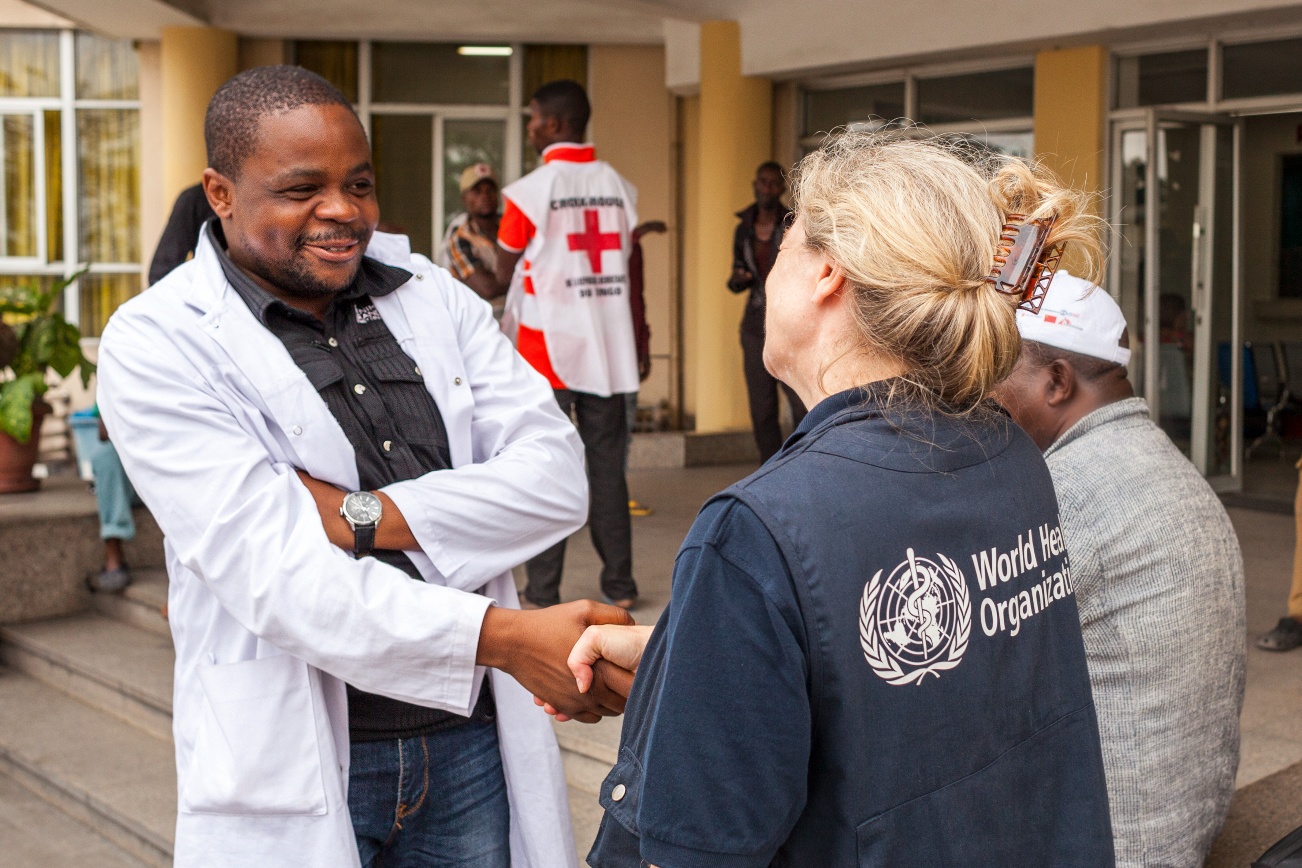 A WHO agent greets a doctor with a handshake.